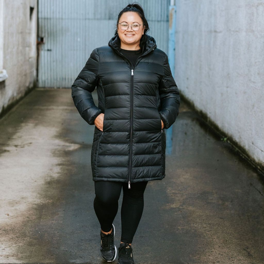 Person wearing a black puffer coat standing in an alleyway.