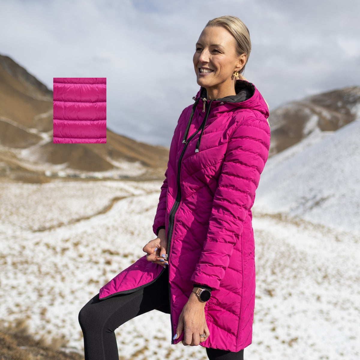Woman wearing a bright magenta Moke long puffer jacket in a snowy mountain landscape.