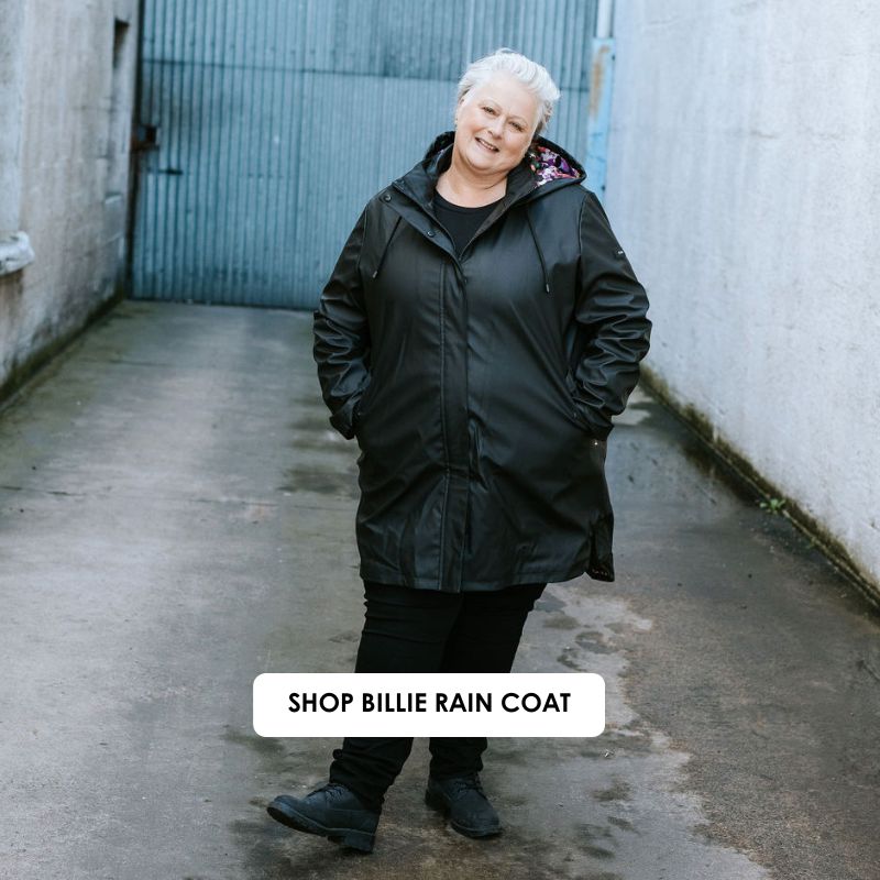 Person wearing a black raincoat standing in an alleyway with 'Shop Billie Rain Coat' text overlay.