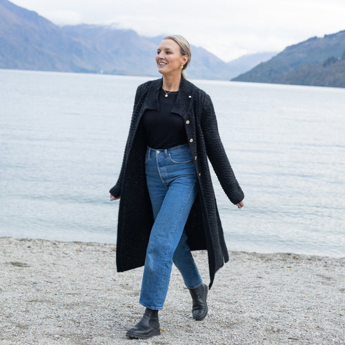 woman in a long cardigan walking by the lake