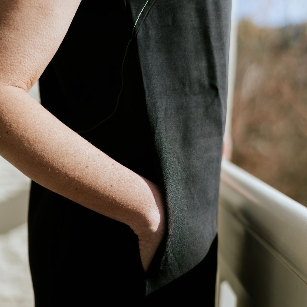 Close-up of a woman's hand in the pocket of a black Moke garment.