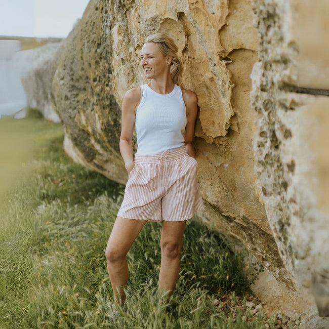 Woman standing against a large rock formation in a natural setting