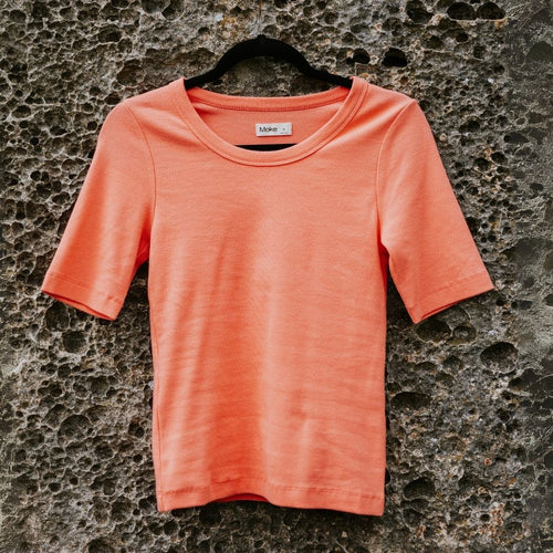 Coral t-shirt on a textured stone wall