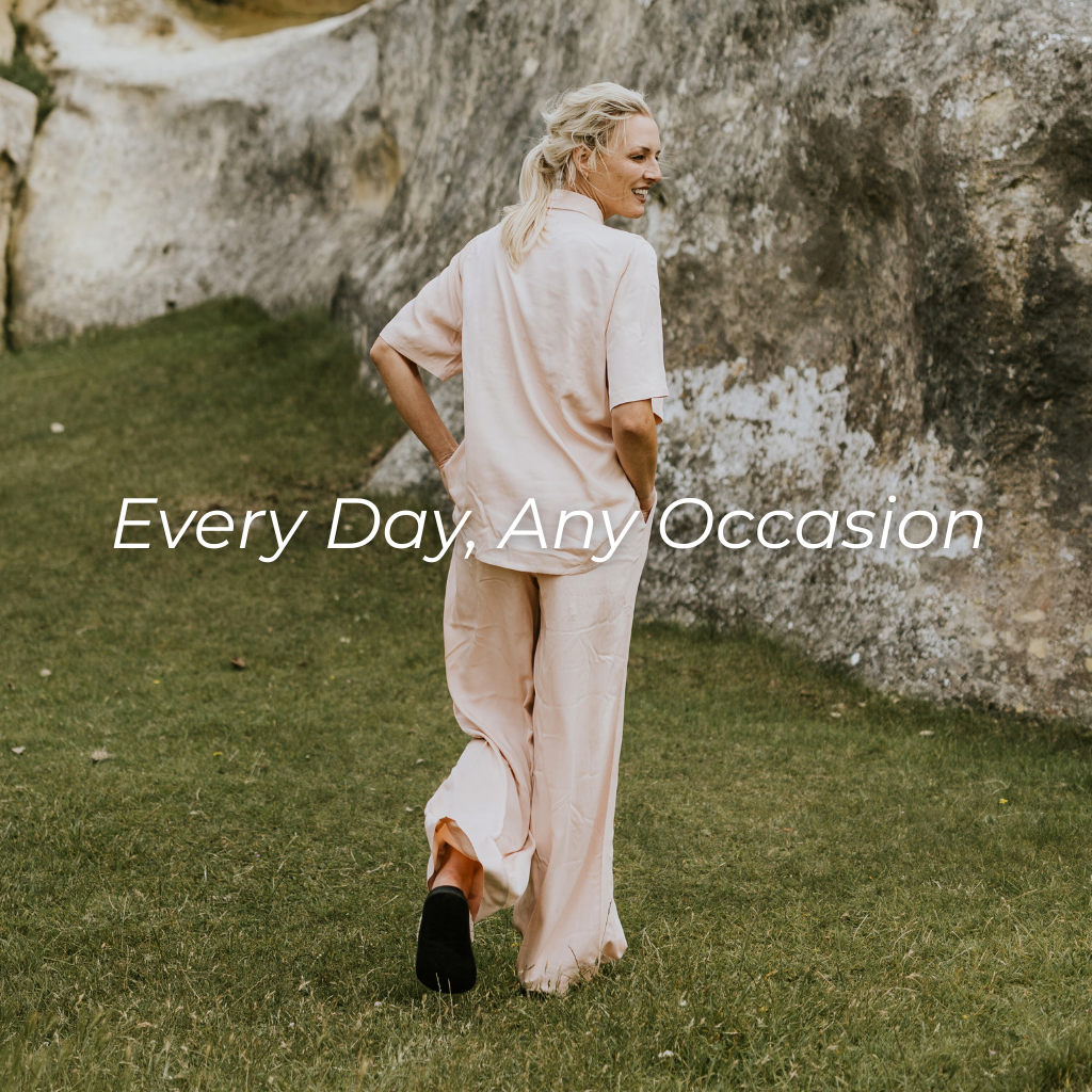 Woman in a pink outfit walking outdoors with text 'Every Day, Any Occasion' on a stone wall background.