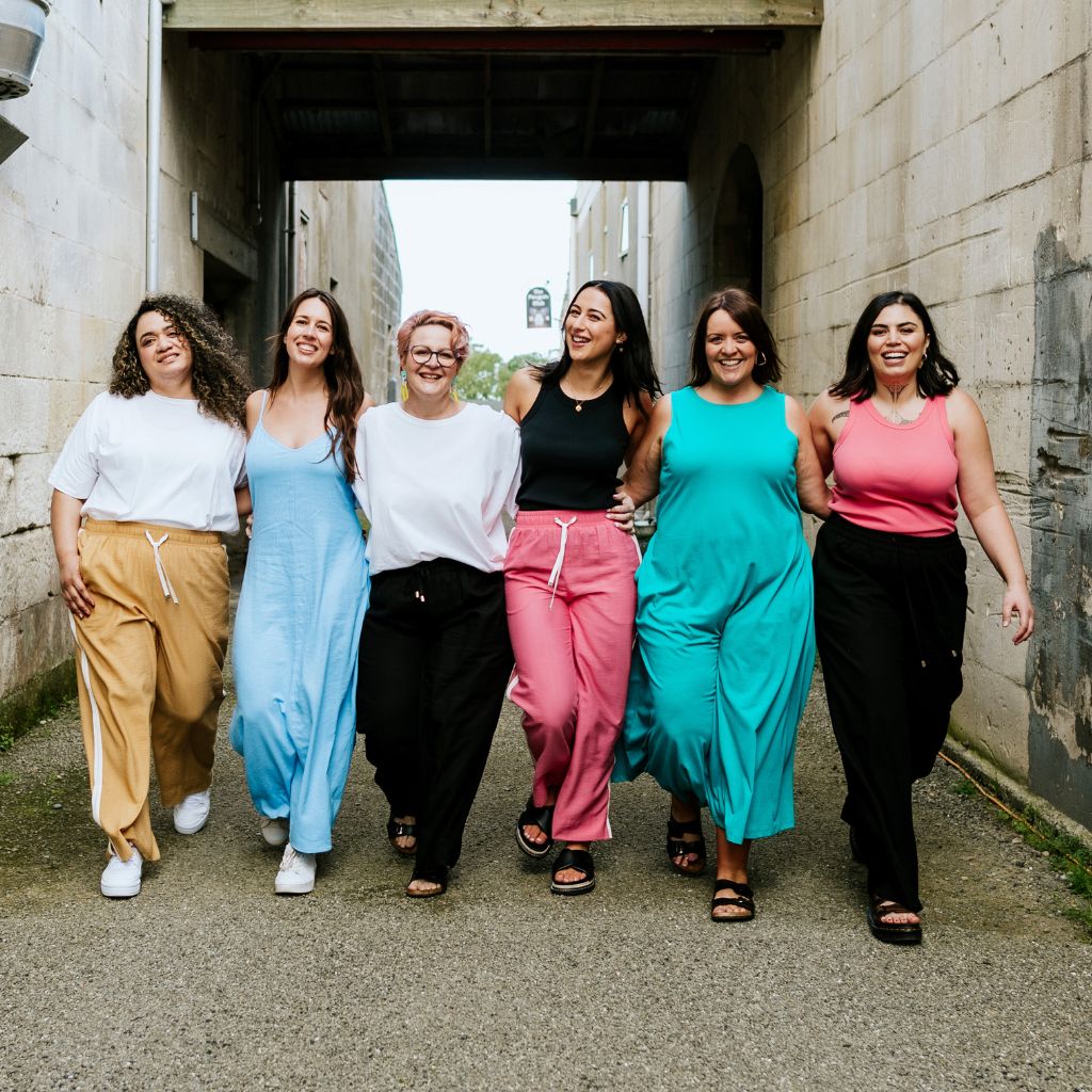 Six women wearing diverse Moke lounge wear walking together in an outdoor alleyway.