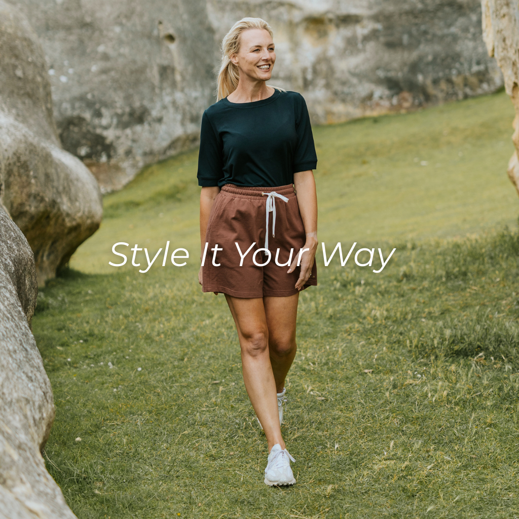 Woman walking outdoors with text 'Style It Your Way' on a grassy area with stone walls.